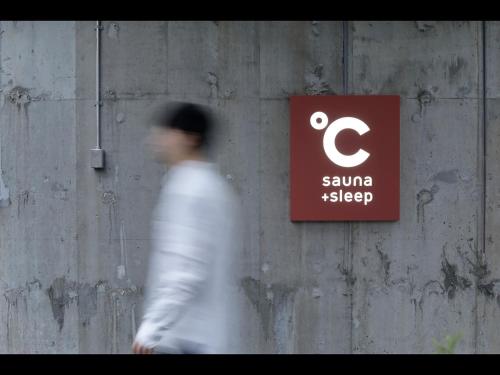 a man walking past a sign on a wall at Do-C Gotanda in Tokyo