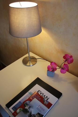 a table with a lamp and a magazine and flowers on it at Hôtel Restaurant le Panorama in Évian-les-Bains