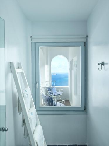a mirror in a white room with a view of the ocean at Lilium Hotel Santorini in Fira