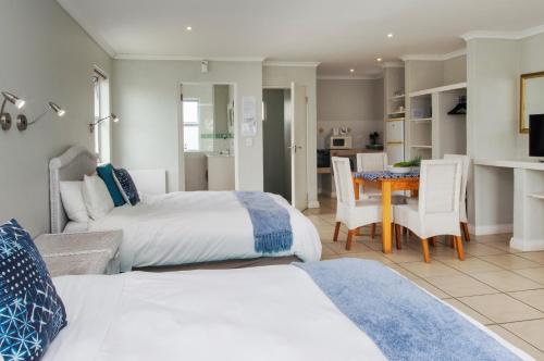 a bedroom with two beds and a dining room with a table at Cape St Francis Resort in Cape St Francis