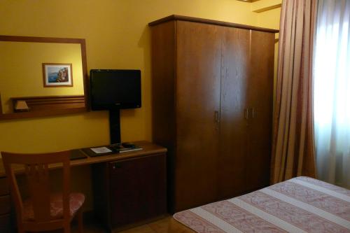 a bedroom with a bed and a desk with a television at Idh Angel in Oviedo