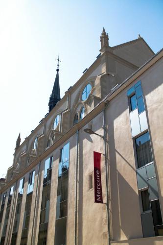 a building with a church steeple in the background at Mercure Poitiers Centre in Poitiers
