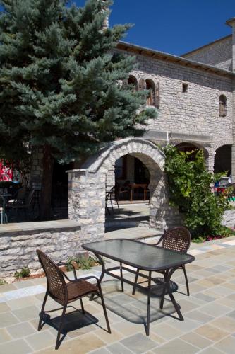a patio with a table and chairs in front of a building at Hotel Monodendri in Monodendri