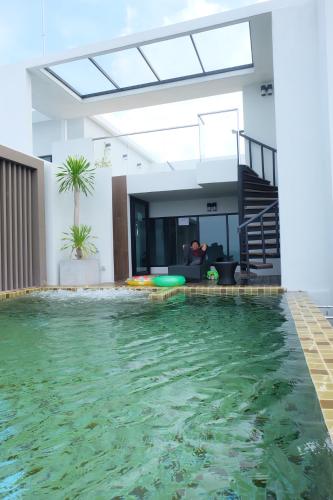 a swimming pool in a living room with a house at Deamber Bangsare Pattaya in Bang Sare
