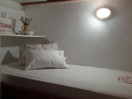 a bed with a white pillow and a light on the wall at Karpathos house in Menetaí