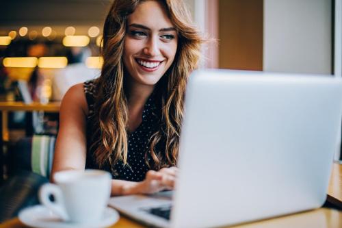 a woman sitting at a table with a laptop computer at Elba Vecindario Aeropuerto Business & Convention Hotel in Vecindario