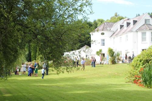 a group of people walking in a yard next to a white house at Innishannon House Hotel in Inishannon