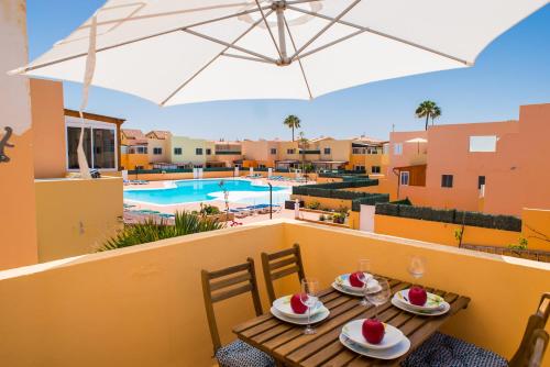 un balcón con una mesa con comida y una sombrilla en Apartment Delfines Sand Corralejo By Holidays Home, en Corralejo