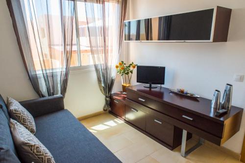 sala de estar con sofá y escritorio con TV en Apartment Delfines Sand Corralejo By Holidays Home, en Corralejo
