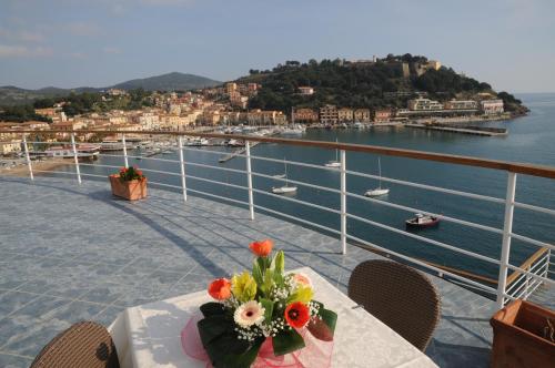 a table with a bouquet of flowers on a balcony at Hotel Plaza in Porto Azzurro