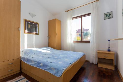 sypialnia z łóżkiem z niebieską kołdrą i oknem w obiekcie Apartment Stanka w mieście Cavtat