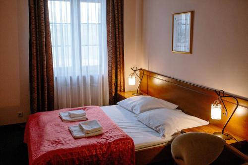 1 dormitorio con 1 cama con 2 toallas en Pałac Koronny Noclegi & Wypoczynek en Wodzisław