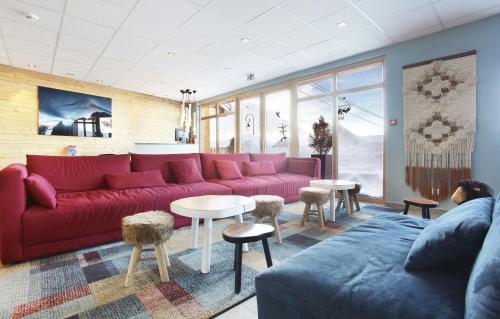 a living room with a red couch and tables at Résidence Odalys Front de Neige in Plagne Villages