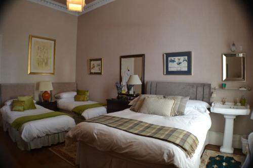 a bedroom with two beds and a sink in it at Maybank Guest House in Helensburgh
