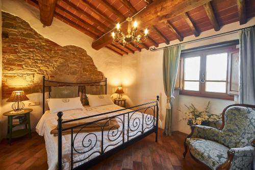 um quarto com uma cama, uma cadeira e um lustre em Ventena Vecchia antico frantoio em Montevarchi