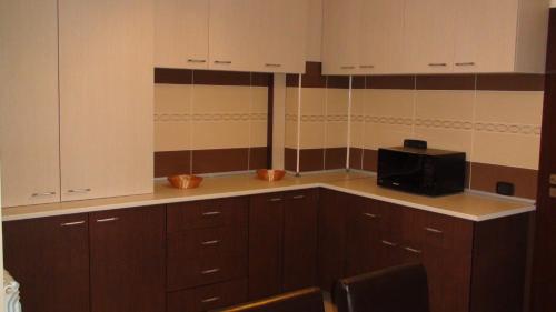 a kitchen with wooden cabinets and a microwave at Vila Ando Mamaia Nord in Mamaia Sat/Năvodari