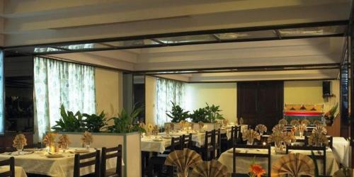 ein Esszimmer mit Tischen, Stühlen und weißem Tischtuch in der Unterkunft Sivaranjani Hotel in Hosur