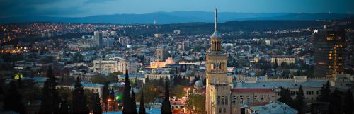 una vista de la ciudad por la noche con un edificio alto en Tbilisi View Hotel, en Tiflis