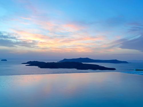 an island in the water with a cloudy sky at Lilium Hotel Santorini in Fira