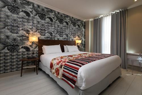 a hotel room with a large bed and a wall mural at R&eacute;sidence & Spa Le Prince R&eacute;gent in Paris