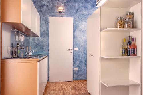 a kitchen with white cabinets and a blue wall at Casale del Mare in Castiglioncello