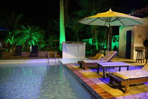 - une piscine avec 2 chaises et un parasol dans l'établissement Pousada Solar Dos Corais, à Búzios