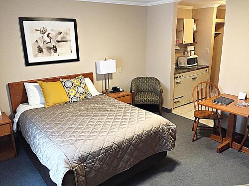 a bedroom with a bed and a table and a kitchen at Coastal Inn Dartmouth in Halifax