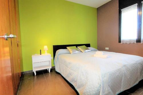 a bedroom with a bed and a green wall at Marina Beach Hollidays Mimosa in Empuriabrava