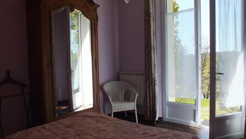 a bedroom with a bed and a chair and windows at Les Grillons du Morvan in Montsauche