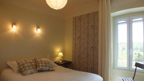 a bedroom with a bed and a large window at Les Grillons du Morvan in Montsauche