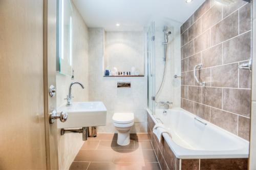 a bathroom with a sink and a toilet and a tub at Mercure Stratford Upon Avon Shakespeare Hotel in Stratford-upon-Avon