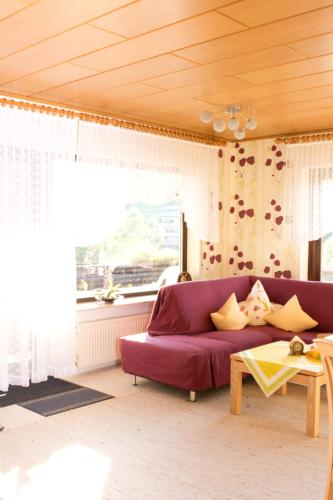 a living room with a purple couch and a window at Gästehaus Cornelia in Wildensee