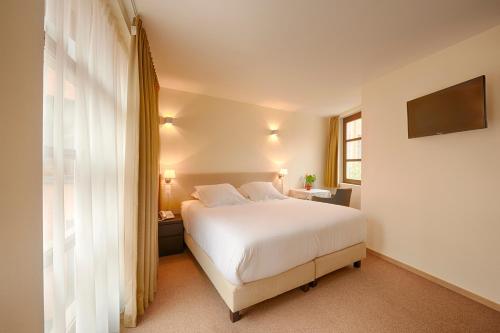 a bedroom with a white bed and a window at Hotel 't Putje in Bruges