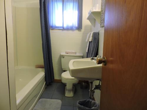La salle de bains est pourvue de toilettes, d'un lavabo et d'une baignoire. dans l'établissement Centennial Cottages, à Brackley Beach