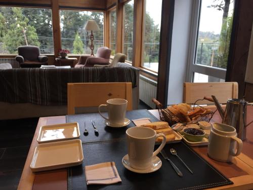 una mesa con dos tazas y un plato de comida en Hostería Las Cumbres en Villa La Angostura