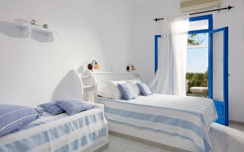 two beds in a white room with a window at Efi Studios in Pollonia