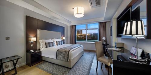 a bedroom with a bed and a desk and a window at Fraser Suites Abuja in Abuja