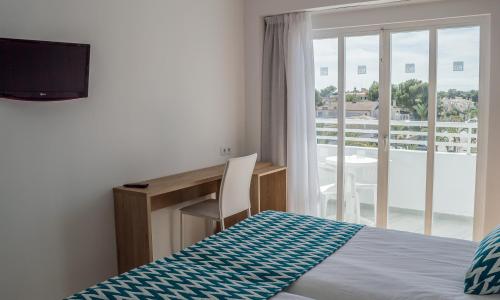 a bedroom with a bed and a desk and a window at BQ Sarah -Adults Only in Can Picafort