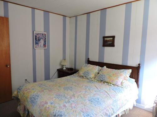 - une chambre avec un lit à rayures bleues et blanches dans l'établissement Centennial Cottages, à Brackley Beach