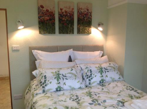 a bedroom with a bed with two paintings on the wall at East Hillerton House in Crediton