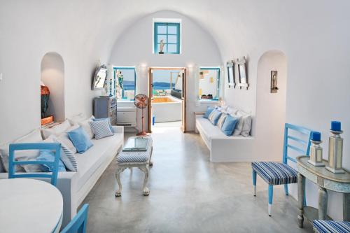 una sala de estar blanca con muebles azules y blancos en EverBlue Cave house by Thireon en Oia