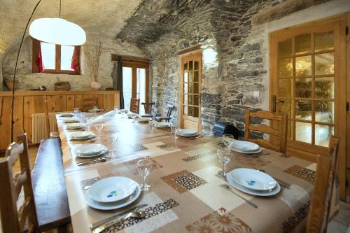 a dining room with a long table with plates and wine glasses at Le Chalet du Villard in Saint-André