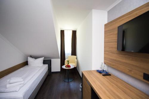 a hotel room with a bed and a flat screen tv at Hotel am See in Tutzing