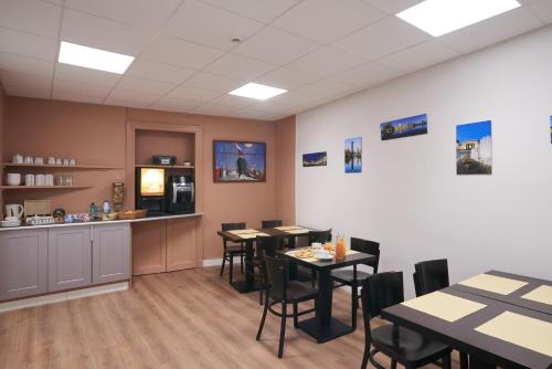 a dining room with tables and chairs and a counter at Hotel Le Petit Duquesne in Nantes