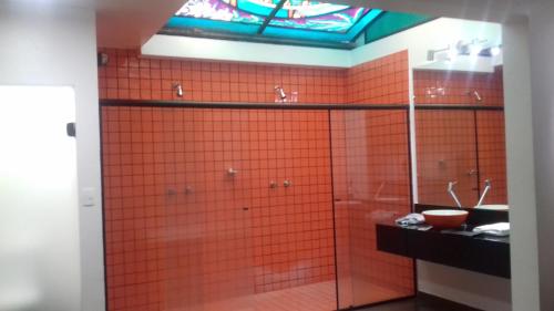 y baño con azulejos de color naranja, ducha y lavamanos. en Elegance Motel, en São Paulo