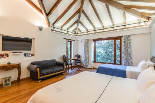 a bedroom with two beds and a flat screen tv at La Casa Del Arbol Hotel Boutique Villa de Leyva in Villa de Leyva