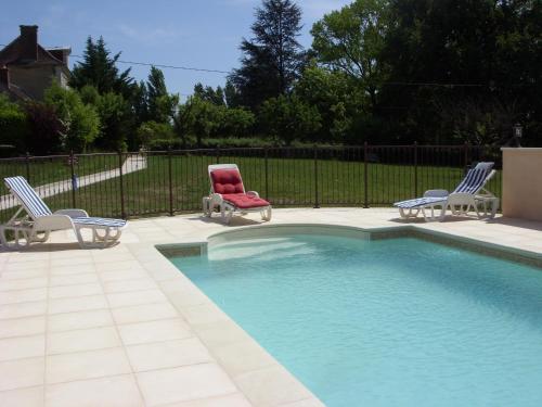 a pool with two lawn chairs and a red chair at Domaine de Sainte Anne in Venoy