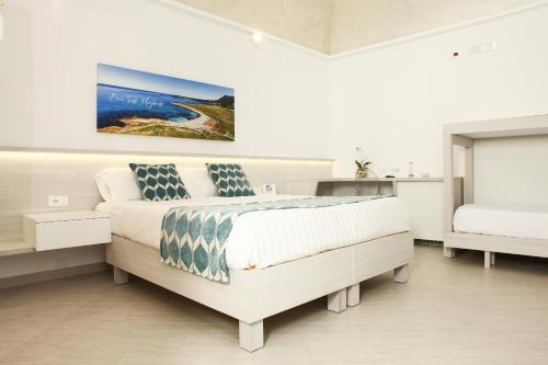 a white bedroom with a bed and a painting on the wall at La Nicchia Smart in San Vito lo Capo