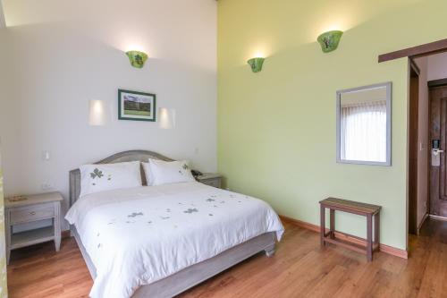 a bedroom with a white bed and a wooden floor at La Casa Del Arbol Hotel Boutique Villa de Leyva in Villa de Leyva