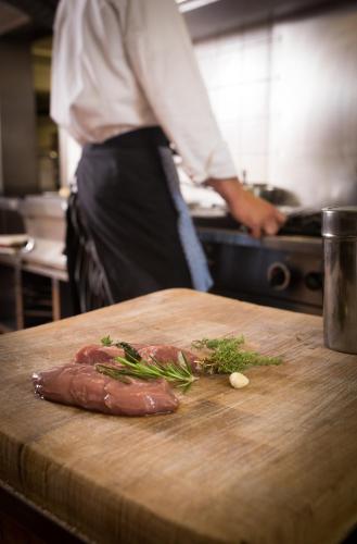 a person in a kitchen preparing food on a cutting board at Brennereihotel Sponsel in Kirchehrenbach